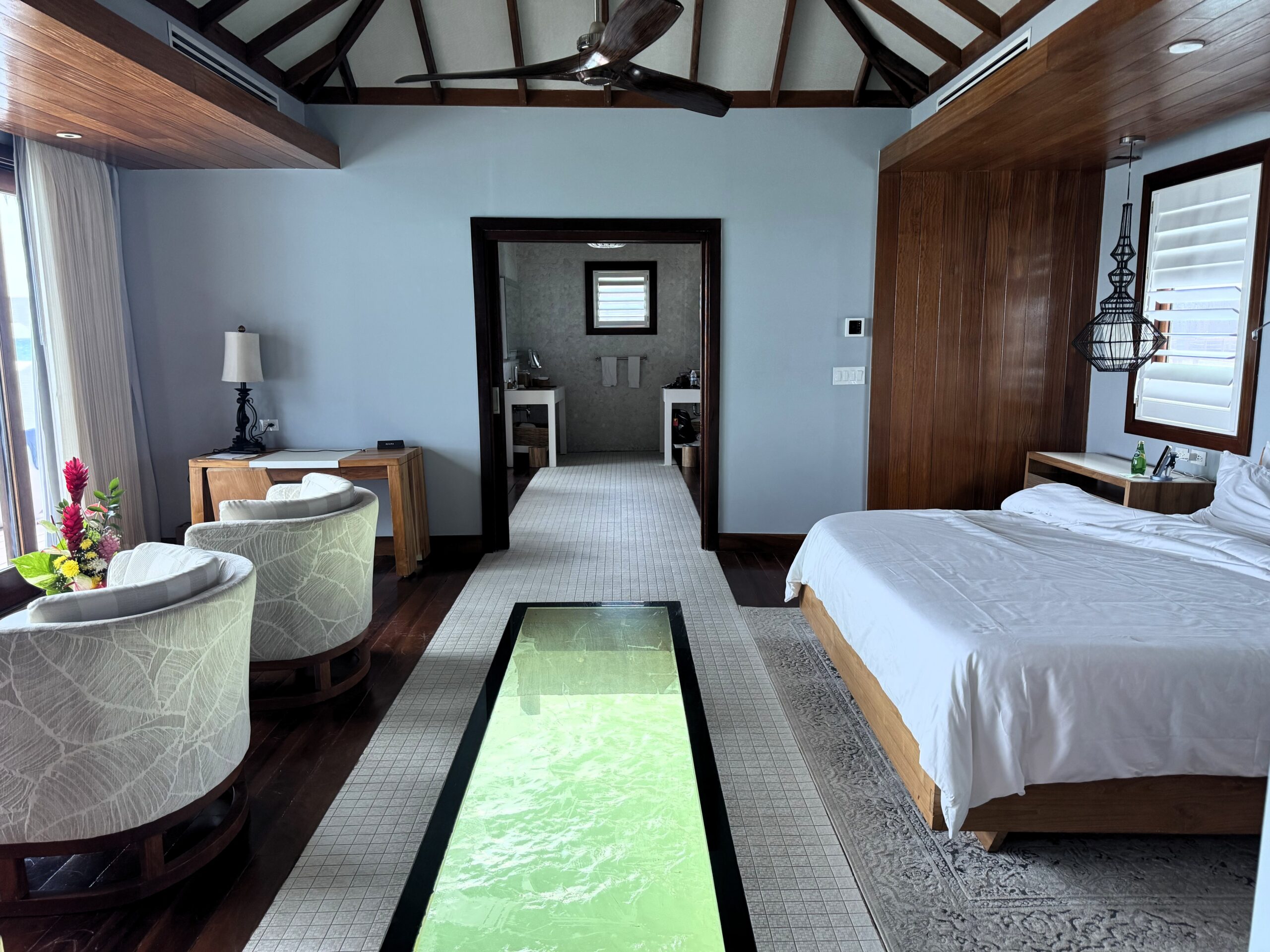 Glass floor panel and bedroom of the Overwater Private Island Butler Villa (OWV) at Sandals Caribbean Cay