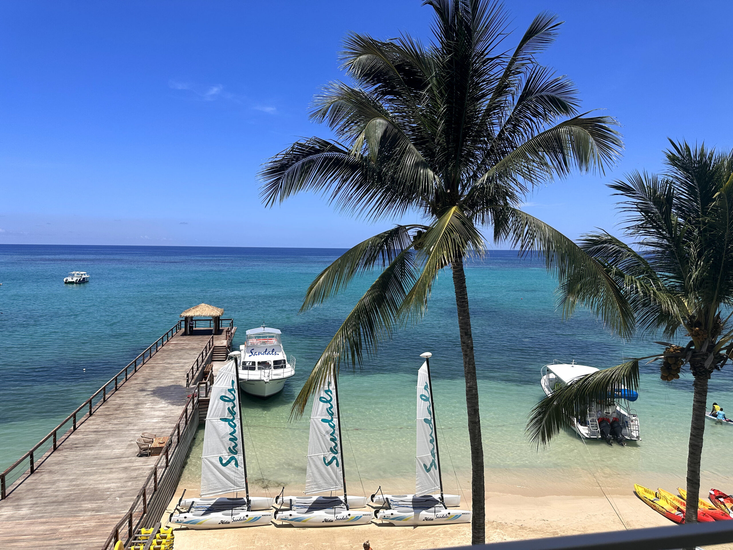 View of the beach, dock, and Sandals watersports boats from the Mammee Bay Beachfront One Bedroom Butler Suite (B1B) at Sandals Dunn's River