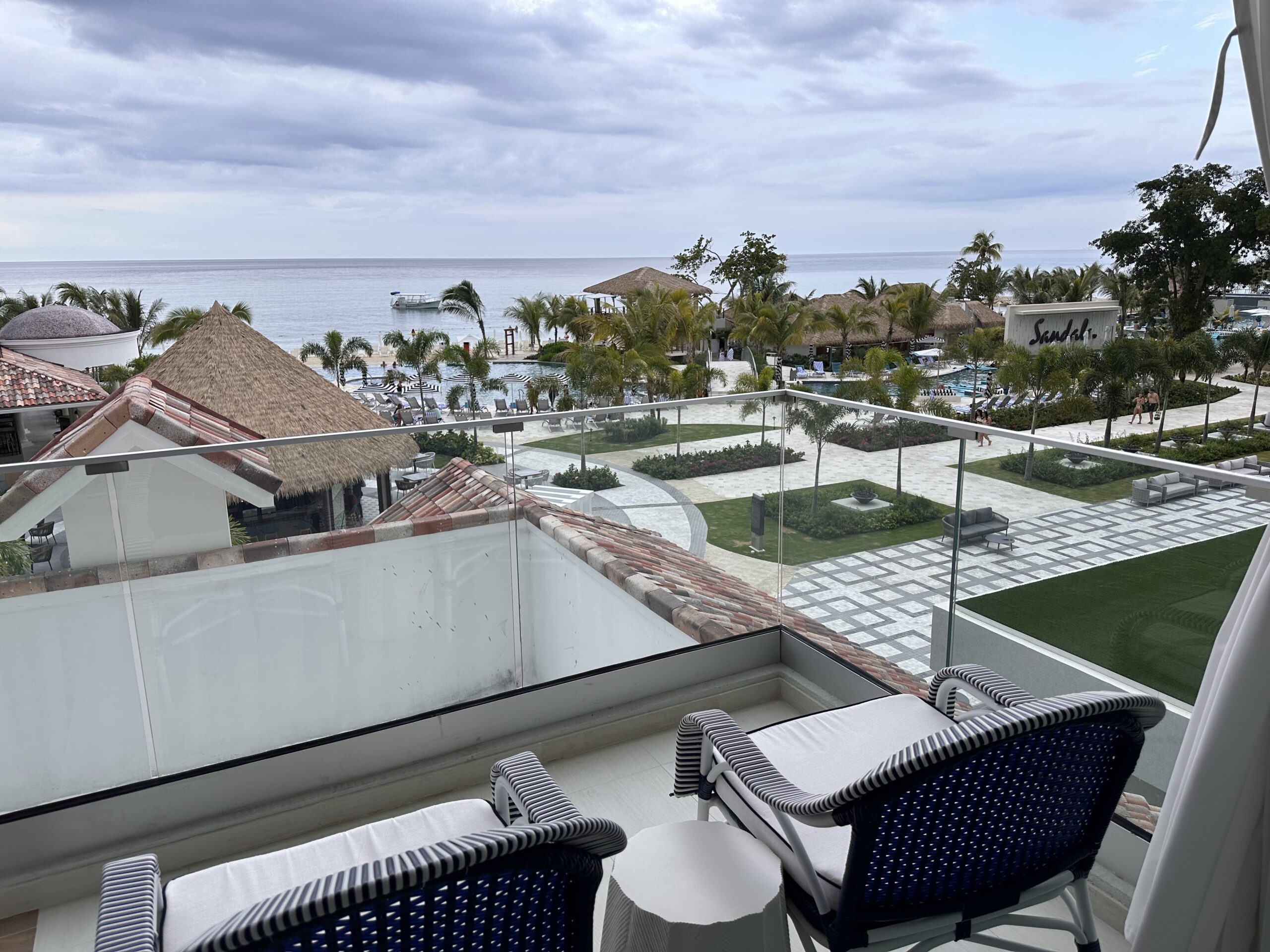 Elevated view from the Travertine Beachfront Club Level Room at Sandals Dunn's River overlooking the resort's landscaped grounds, pools, and coastline.