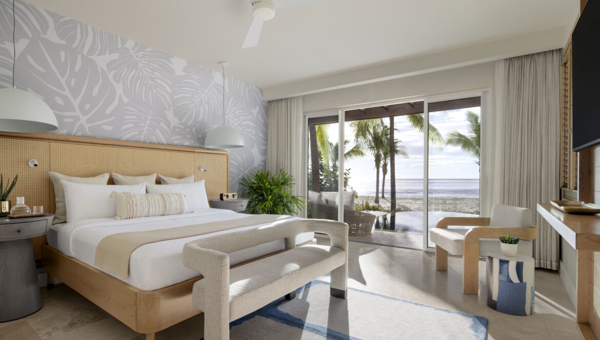 Bedroom in the Beachfront One-Bedroom Butler Villa Suite with Private Pool (BVJP) at Sandals Saint Vincent, with a king bed, cane headboard, and sliding glass doors opening to the pool and beach