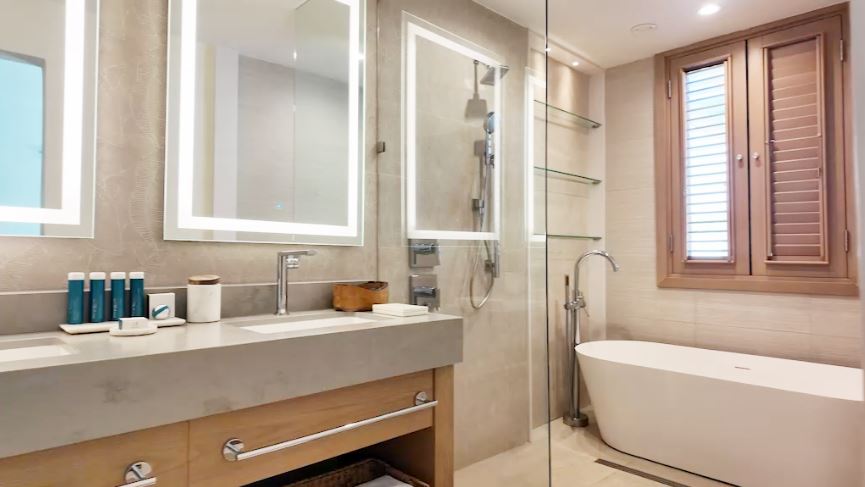 Bathroom in the Butler Villa Suite (VG) at Sandals Saint Vincent, with his-and-her sinks, a walk-in shower, and a freestanding soaking tub