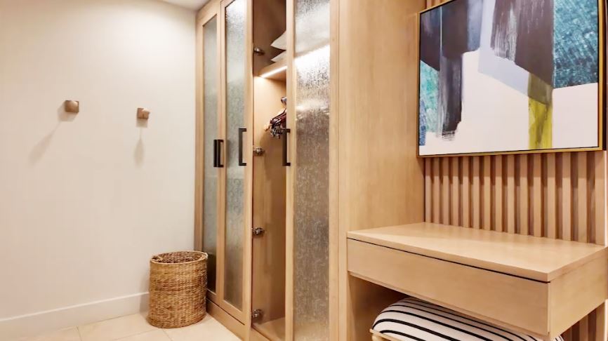 Walk-in closet in the Butler Villa Suite (VG) at Sandals Saint Vincent, with frosted-glass wardrobes, a seat, and abstract art