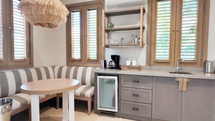 Butler pantry and kitchenette in the Butler Villa Suite (VG) at Sandals Saint Vincent, with a striped banquette, round table, mini fridge, and coffee station