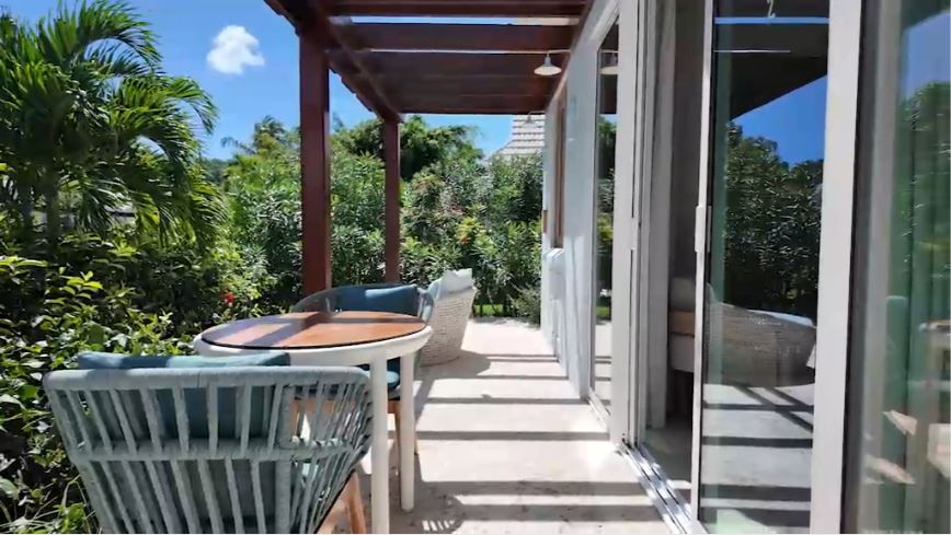 Private garden patio of the Butler Villa Suite (VG) at Sandals Saint Vincent, with a bistro table and chairs under a pergola, surrounded by tropical plants