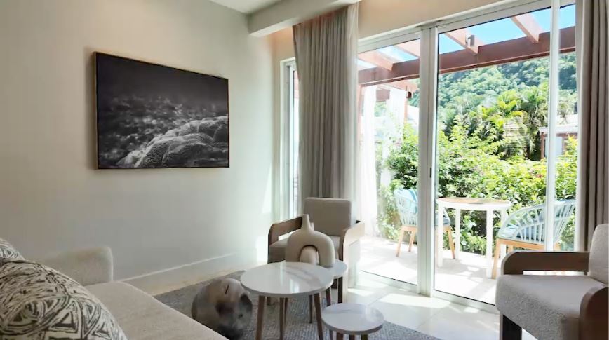 Sitting area in the Butler Villa Suite (VG) at Sandals Saint Vincent, with a sofa, armchairs, and sliding glass doors opening to the patio and garden