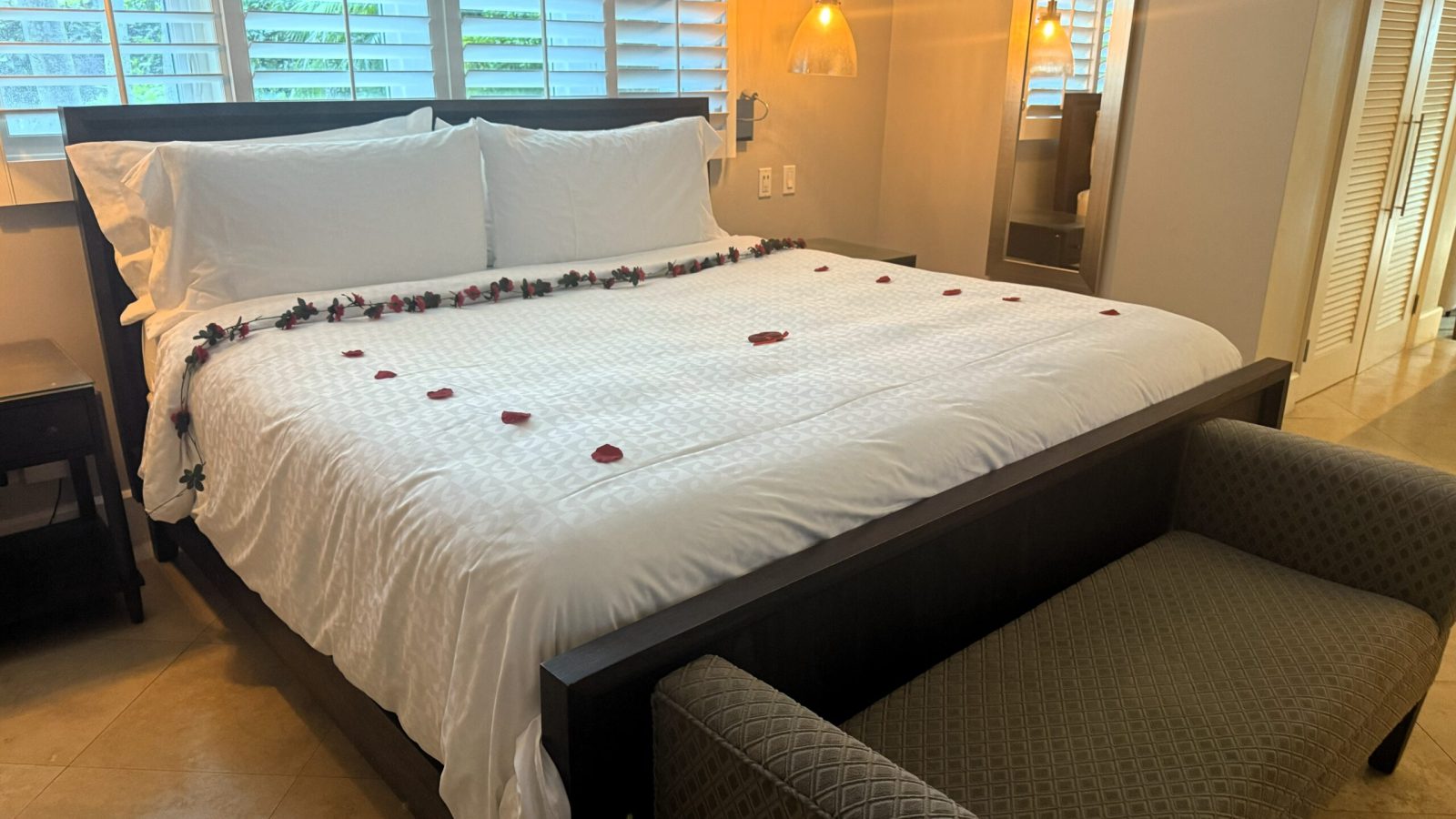 King-size bed at the Sandals Royal Bahamian Island Village One Bedroom Walkout Butler Villa Suite with butler-arranged rose petals and Venetian blinds