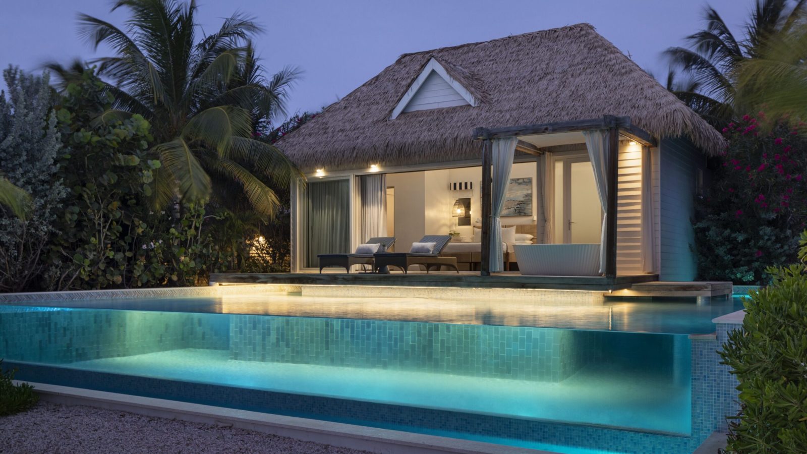 Sandals Royal Curaçao Awa Seaside Bungalow exterior at night with private pool and illuminated interior visible from the beach