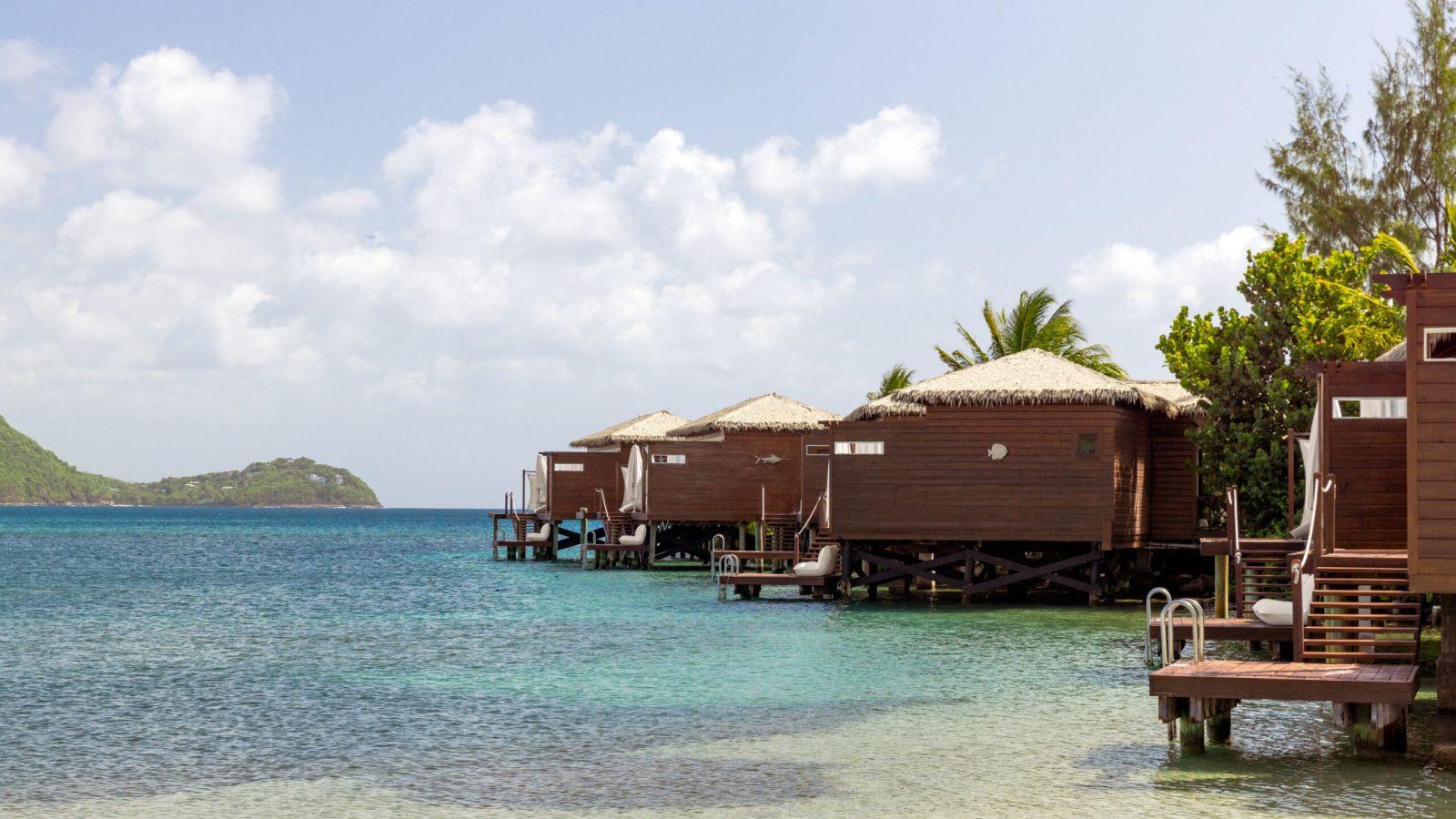 Overwater Honeymoon Butler Bungalows (OWB) at Sandals Grande St. Lucian with thatched roofs over the Caribbean