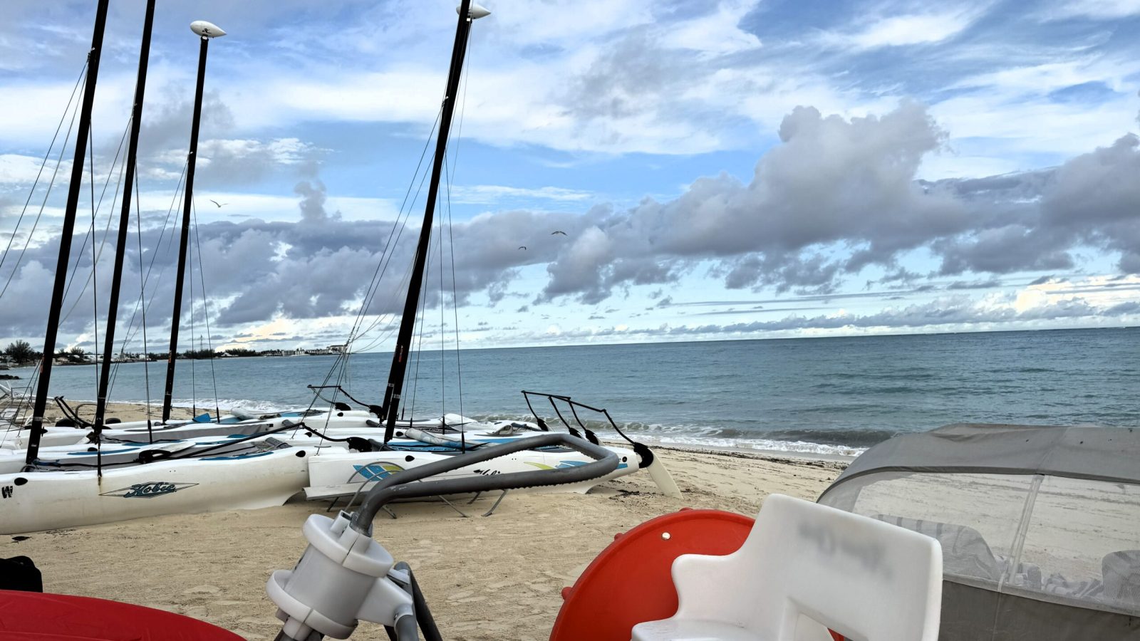 Hobie Cat sailboats and water sports equipment lined up on the beach at the Aqua Center at Sandals Royal Bahamian