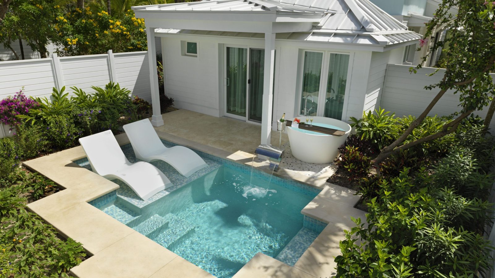 Exterior of the Island Village One Bedroom Butler Villa Suite with Private Pool (V1PP) at Sandals Royal Bahamian, a cottage villa with a private plunge pool, loungers, and a freestanding soaking tub