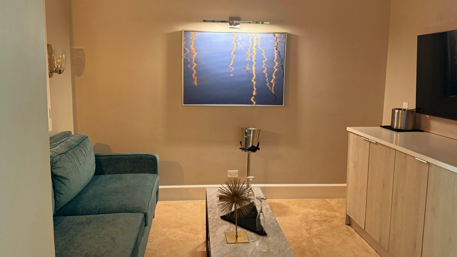 Sitting area in the Island Village One Bedroom Butler Villa Suite with Private Pool (V1PP) at Sandals Royal Bahamian, with a sofa, marble console, and wall-mounted TV