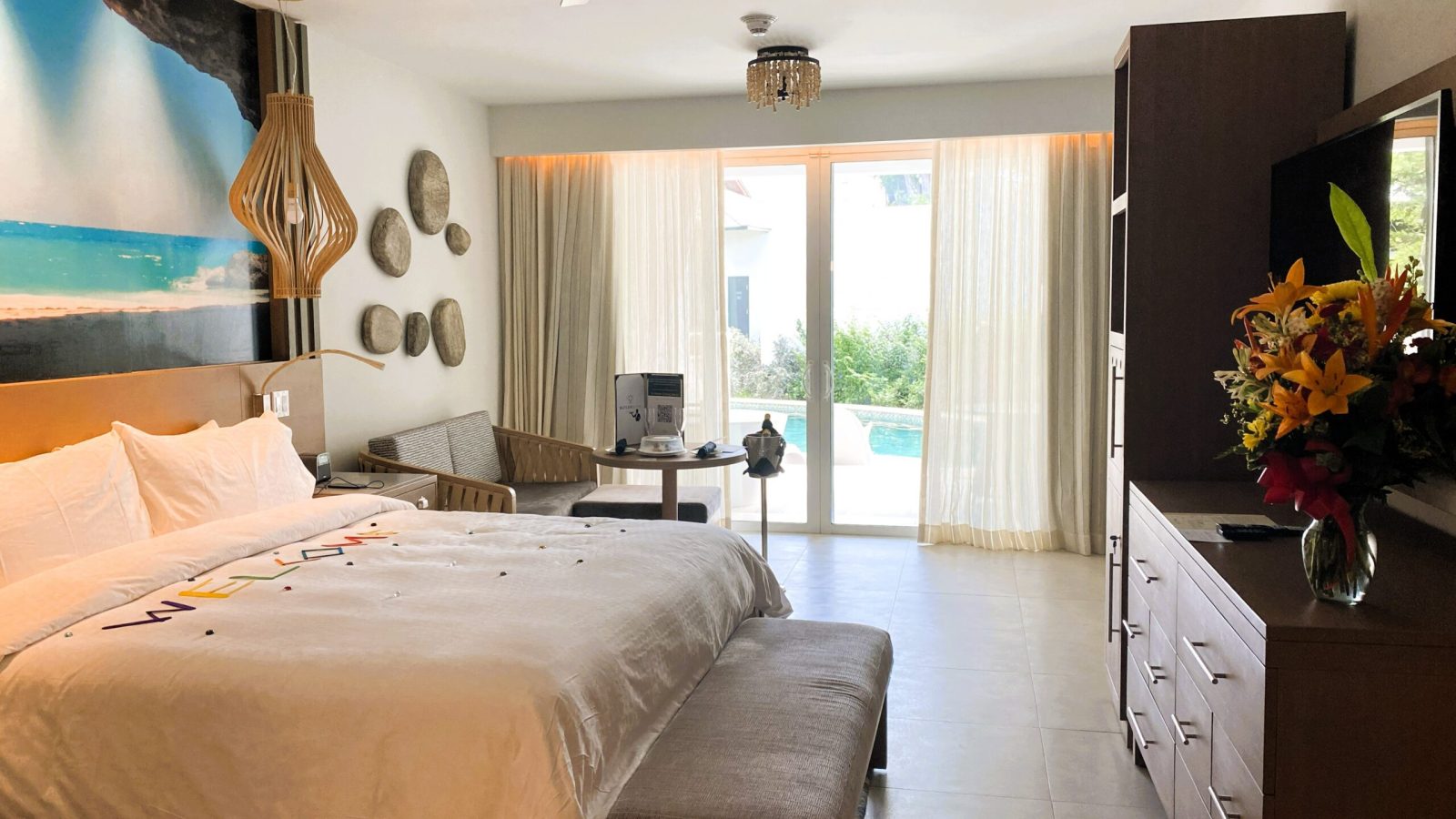 King-size bed and seating area in the Sandals Royal Barbados South Seas Hideaway Crystal Lagoon Swim-up Butler Suite with sliding doors open to the swim-up pool
