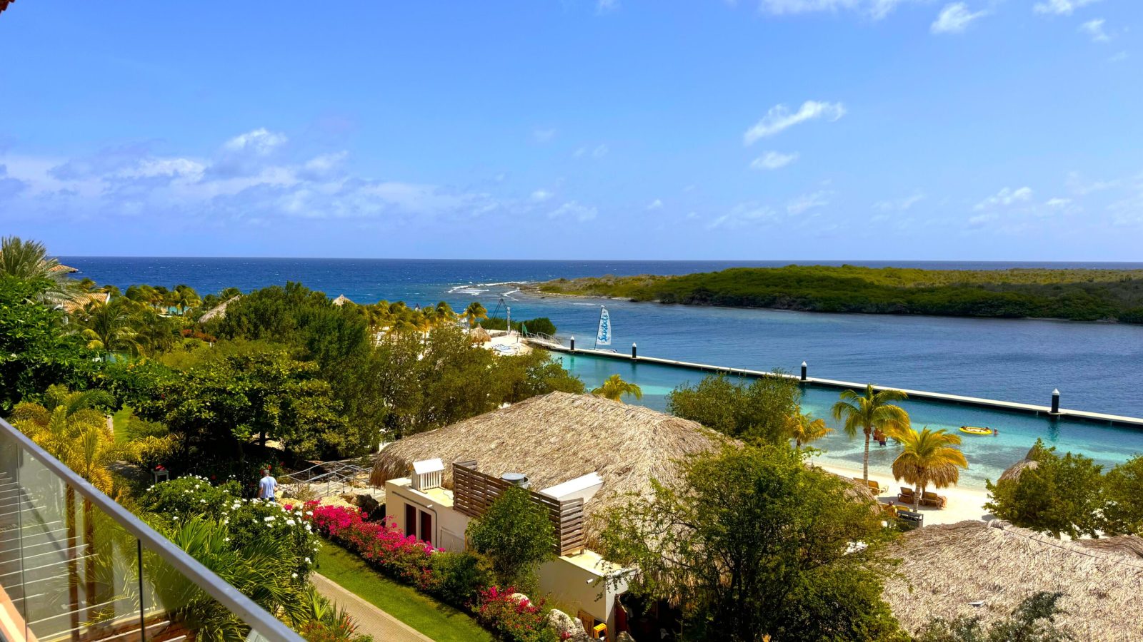 View from Sandals Royal Curaçao Sunchi Beachside Club Level Room balcony overlooking the ocean, harbor inlet, and swimming beach below