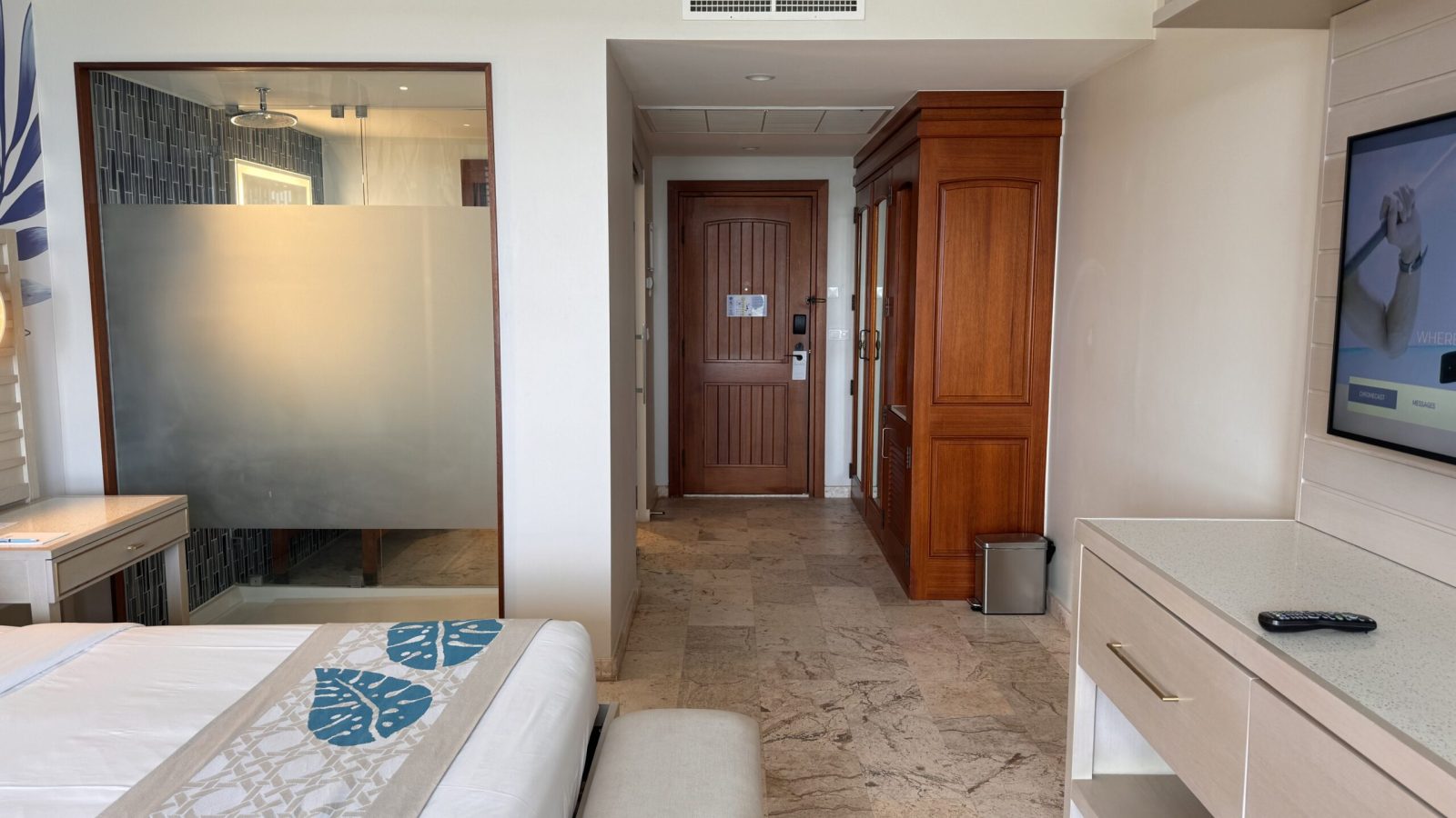 Sandals Royal Curaçao Sunchi Beachside Club Level Room interior showing king bed, light wood finishings, and glass shower window