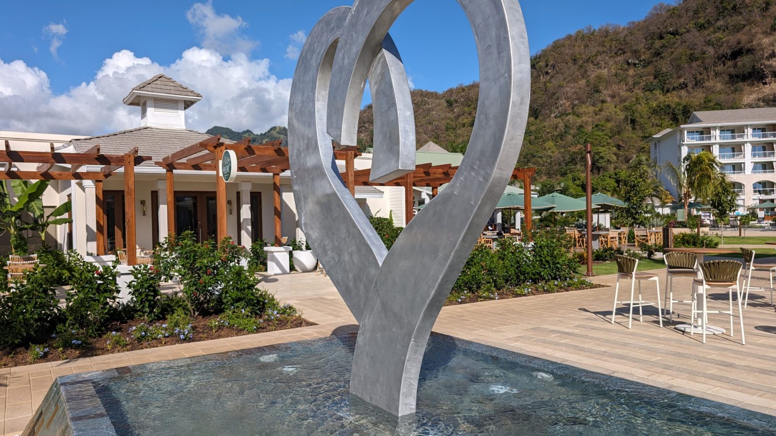 Sandals Saint Vincent heart sculpture fountain in the resort plaza with green mountain peaks behind