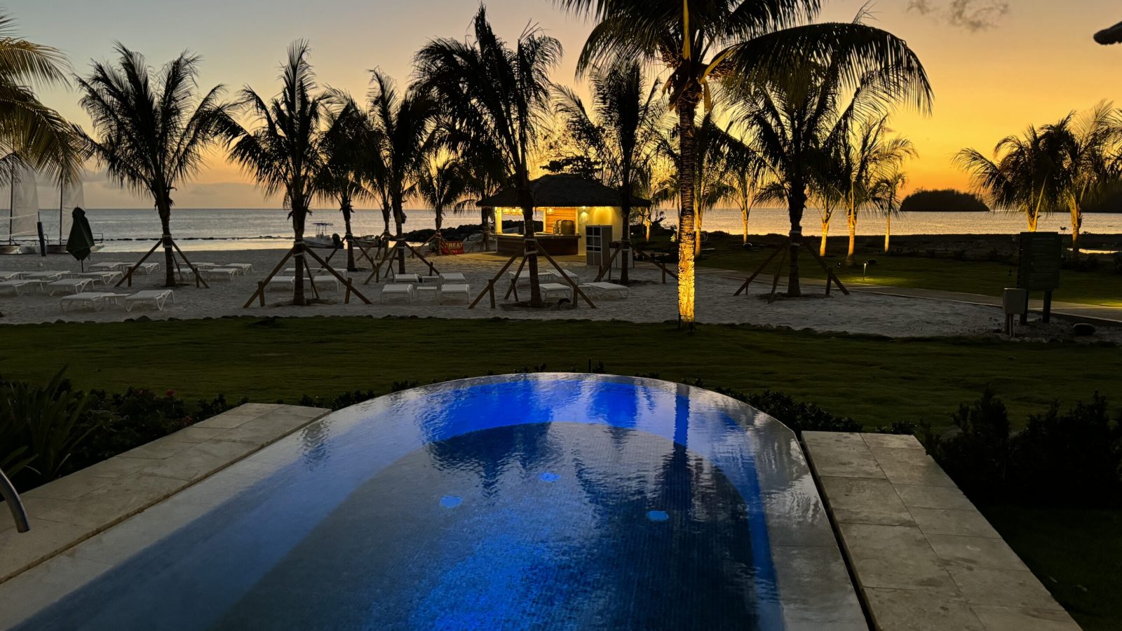 Private pool lit at dusk at the Beachfront One-Bedroom Butler Villa Suite with Private Pool (BVJP) at Sandals Saint Vincent, with palms and a sunset over the ocean